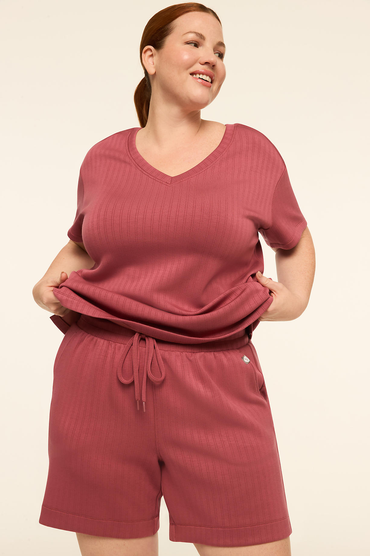 A smiling woman in a rose-colored v-neck top and matching shorts stands against a plain, light-colored background. Product Image 5