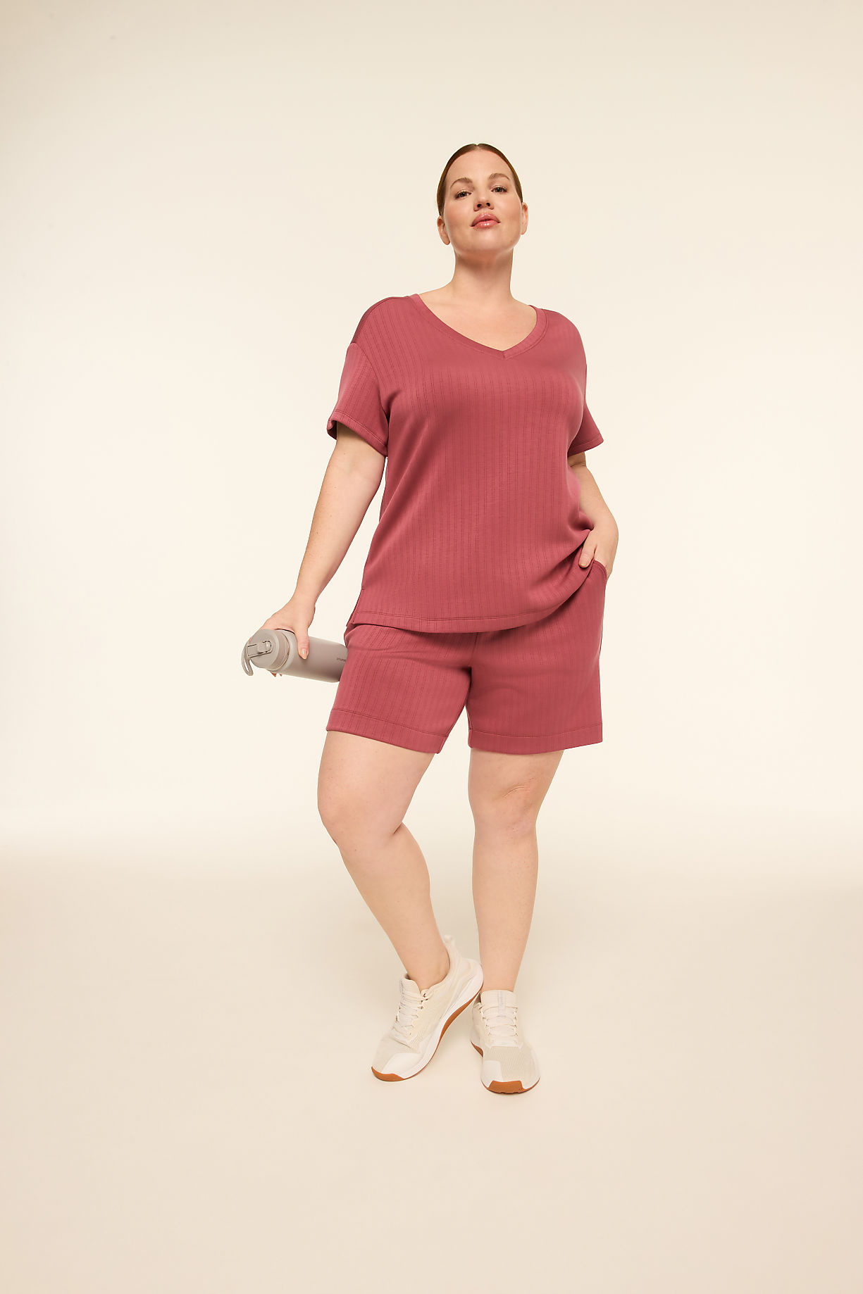 A woman in a rose-colored loungewear set and sneakers stands holding a rolled-up mat against a plain, light-colored background. Product Image 8