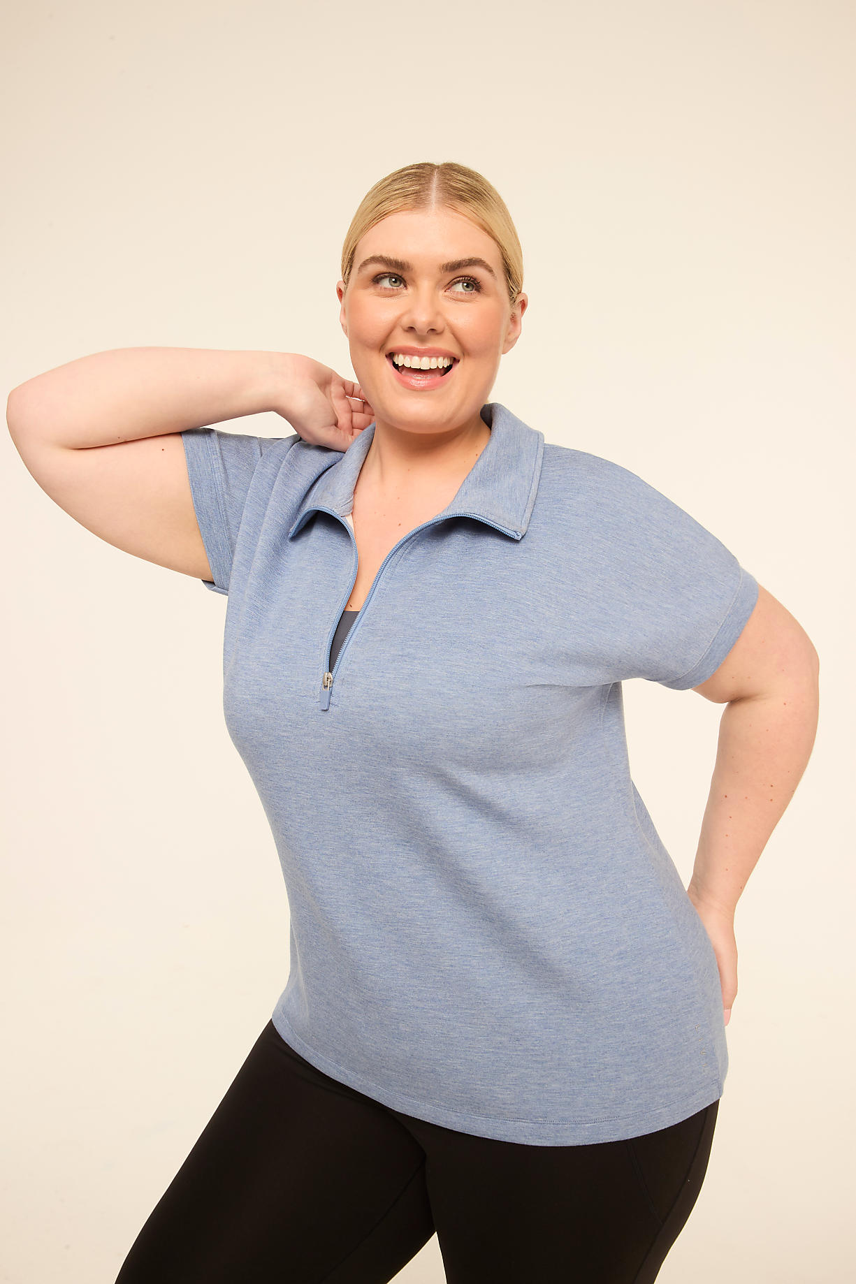 A smiling woman in a blue polo shirt and black pants poses against a plain, light-colored background. Product Image 4
