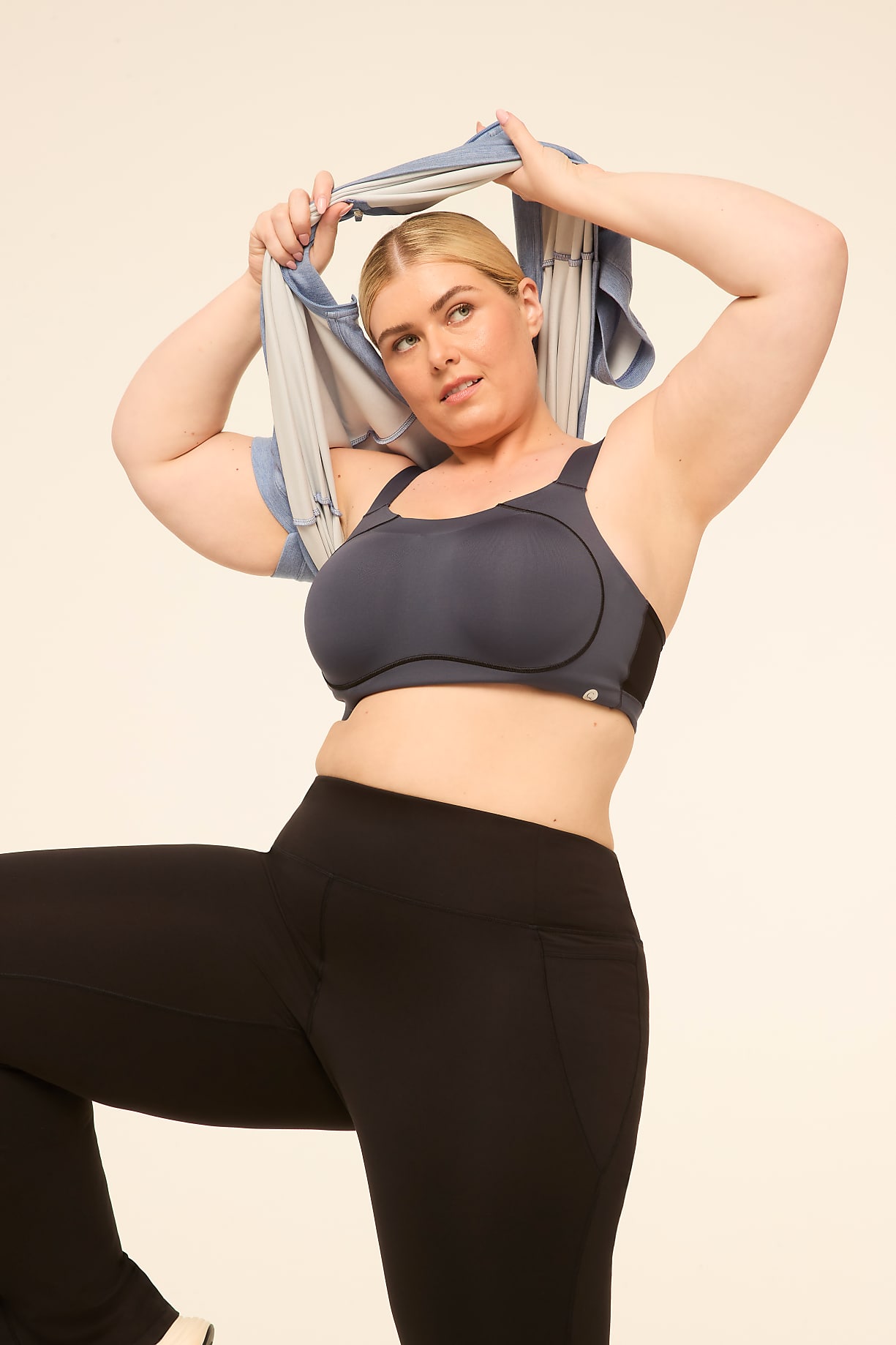A woman in a sports bra and leggings stretches with a towel over her head against a plain background. Product Image 7