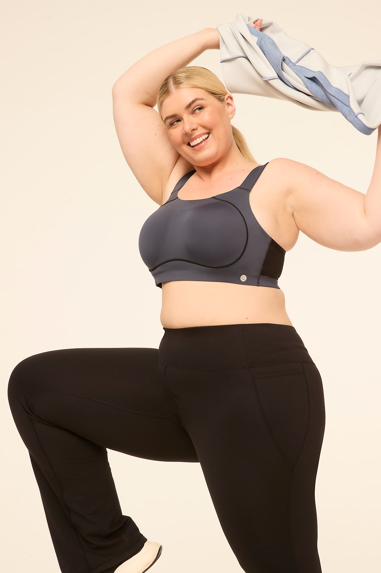 A smiling woman in a sports bra and black leggings strikes a dynamic pose against a plain, light-colored background. Product Image 8