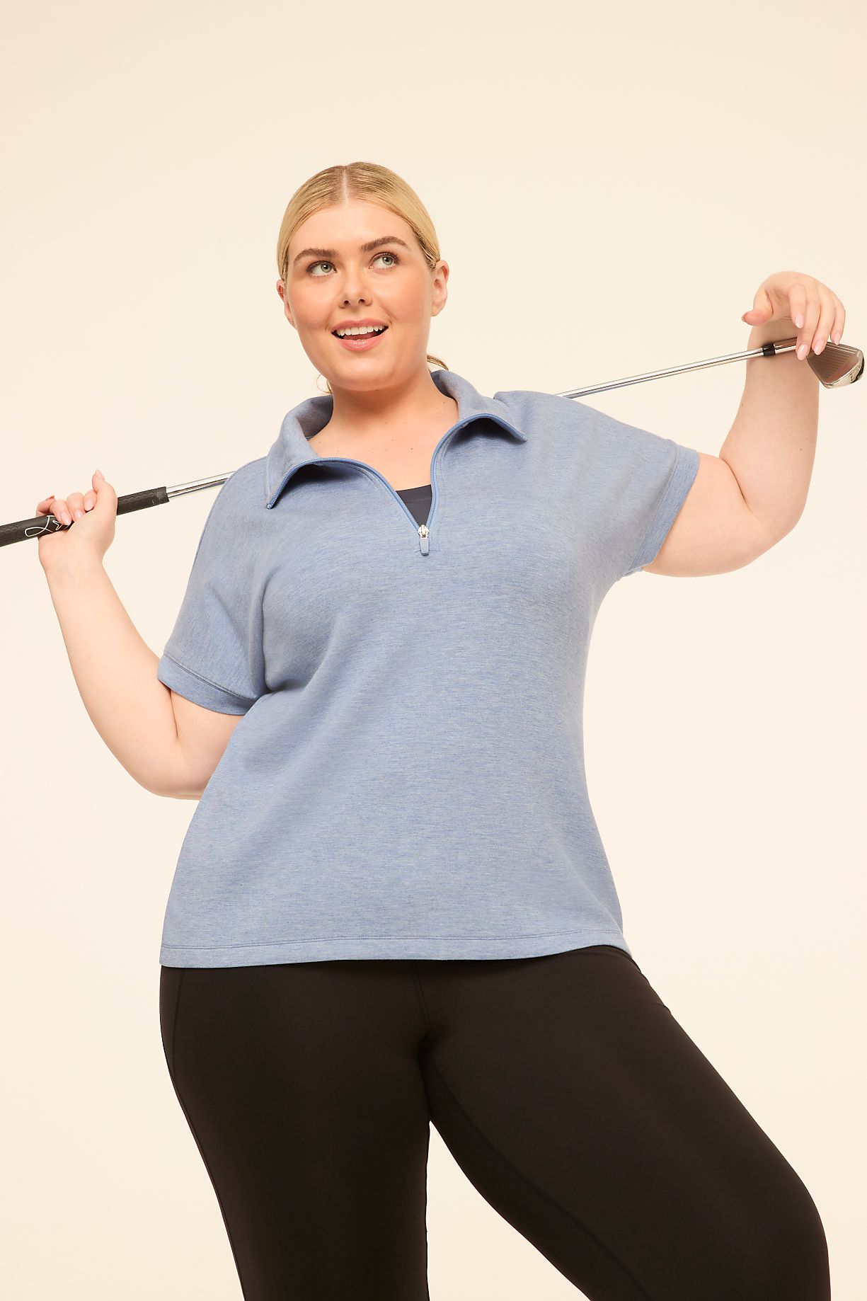 A woman in a blue polo shirt and black leggings holds a golf club over her shoulder against a plain, light-colored background. Product Image 11