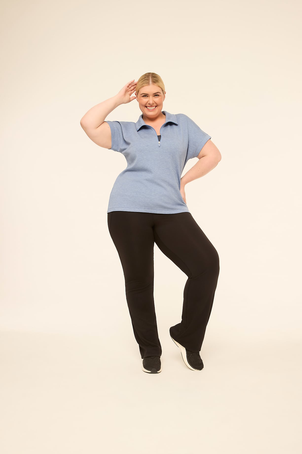 A smiling, plus-size woman in a blue polo shirt and black pants poses against a plain, light-colored background. Product Image 12