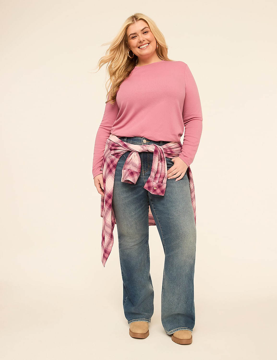 A smiling woman in a pink sweater and jeans stands against a plain, light-colored background, with a plaid shirt tied around her waist. Product Image 3