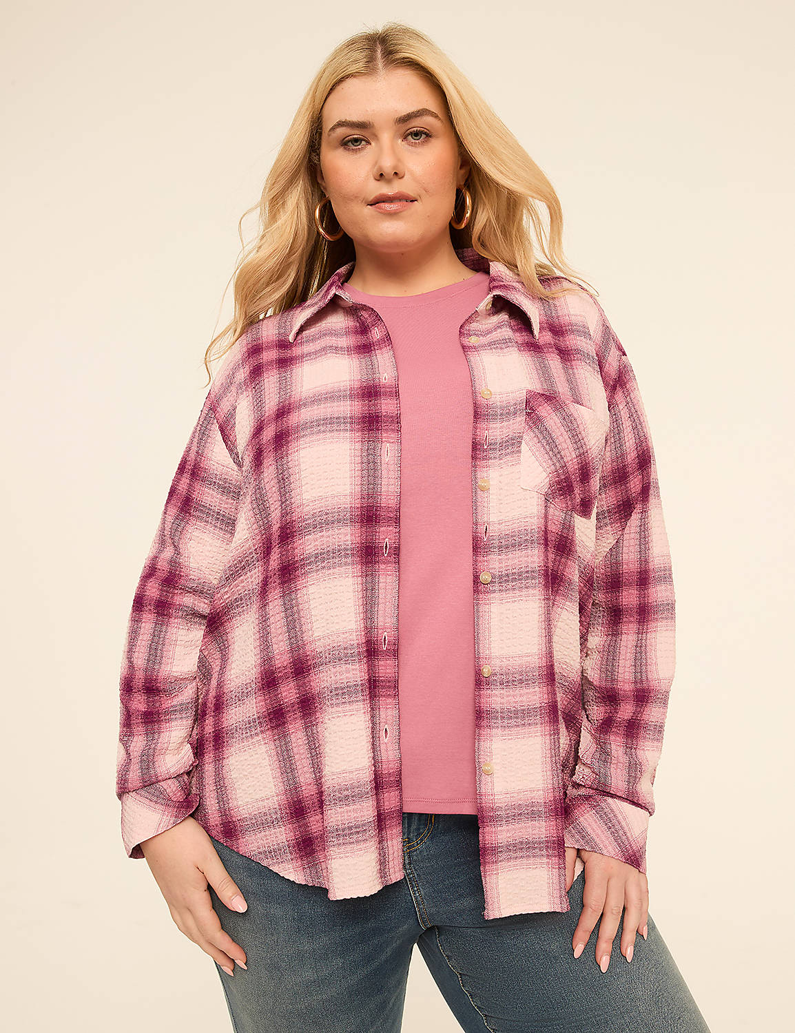 A woman in a pink plaid shirt and jeans stands against a plain, light-colored background. Product Image 1