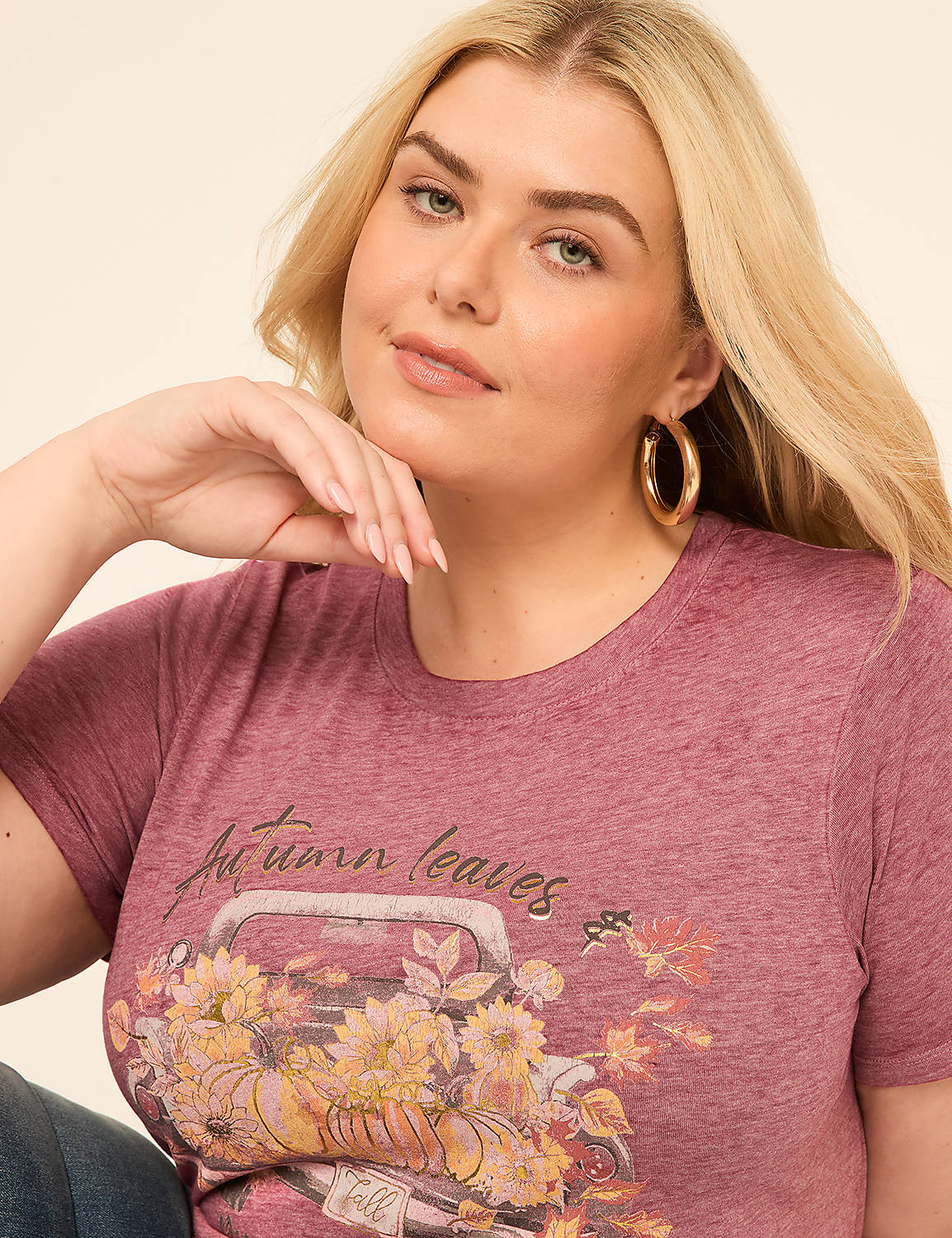 A woman with blonde hair and hoop earrings poses in a maroon t-shirt with an autumn-themed graphic, set against a plain, light-colored background. Product Image 4