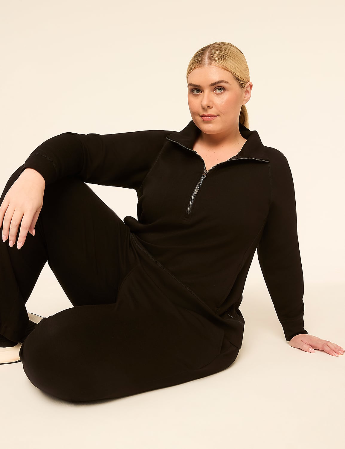 A woman in a black loungewear set sits on a plain, light-colored background. Product Image 3