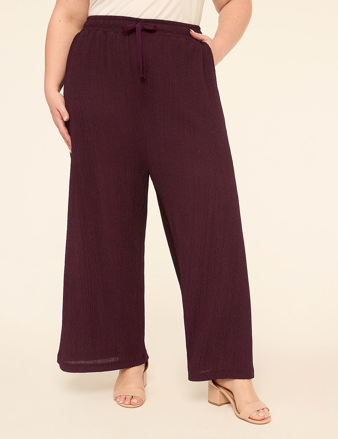 A person wearing plum-colored, wide-leg, textured pants stands against a plain, light-colored background. Product Image 1