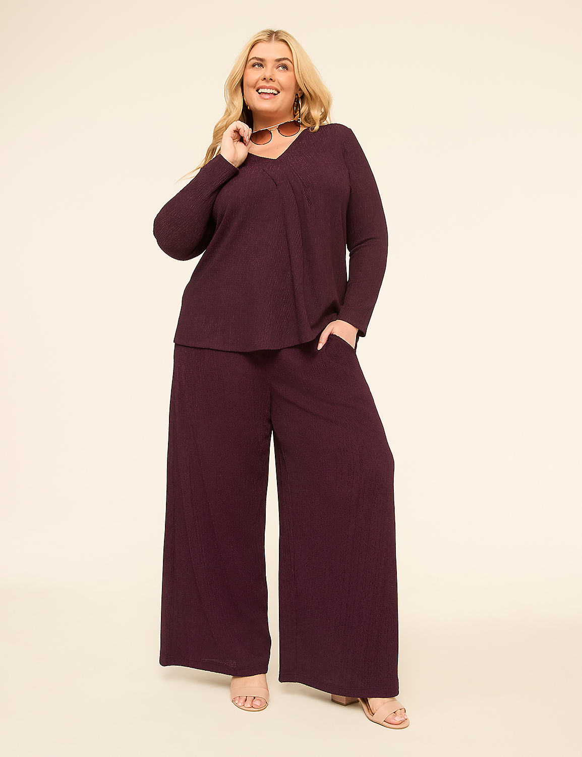 A smiling woman in a plum-colored ribbed loungewear set poses against a plain cream background. Product Image 3