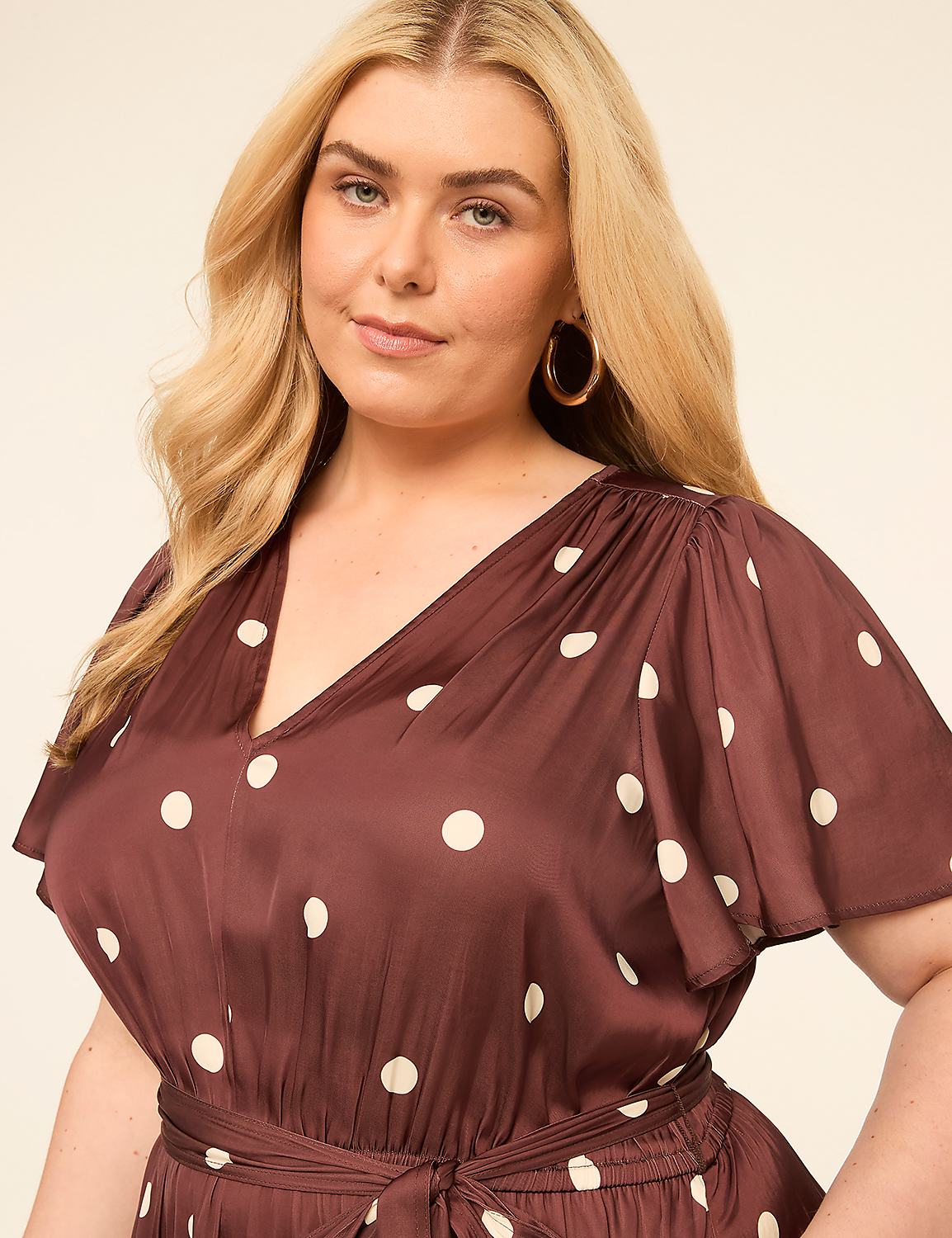 A woman with blonde hair and large hoop earrings poses in a brown polka dot dress against a plain, light-colored background. Product Image 3
