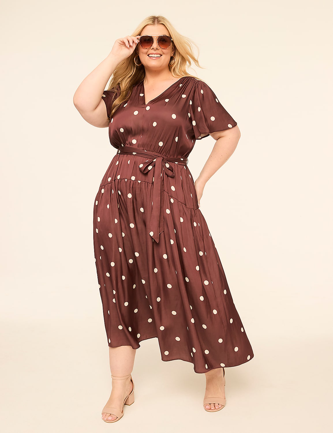 A smiling woman in a polka-dot dress poses against a plain, light-colored background. Product Image 1