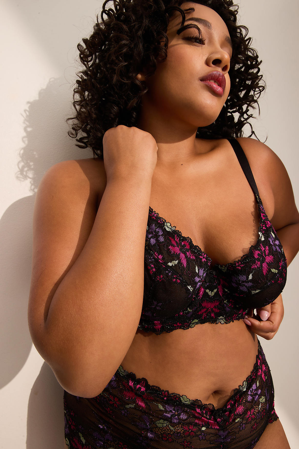 A woman in a floral lace bra and underwear stands against a white wall with shadows. Product Image 8