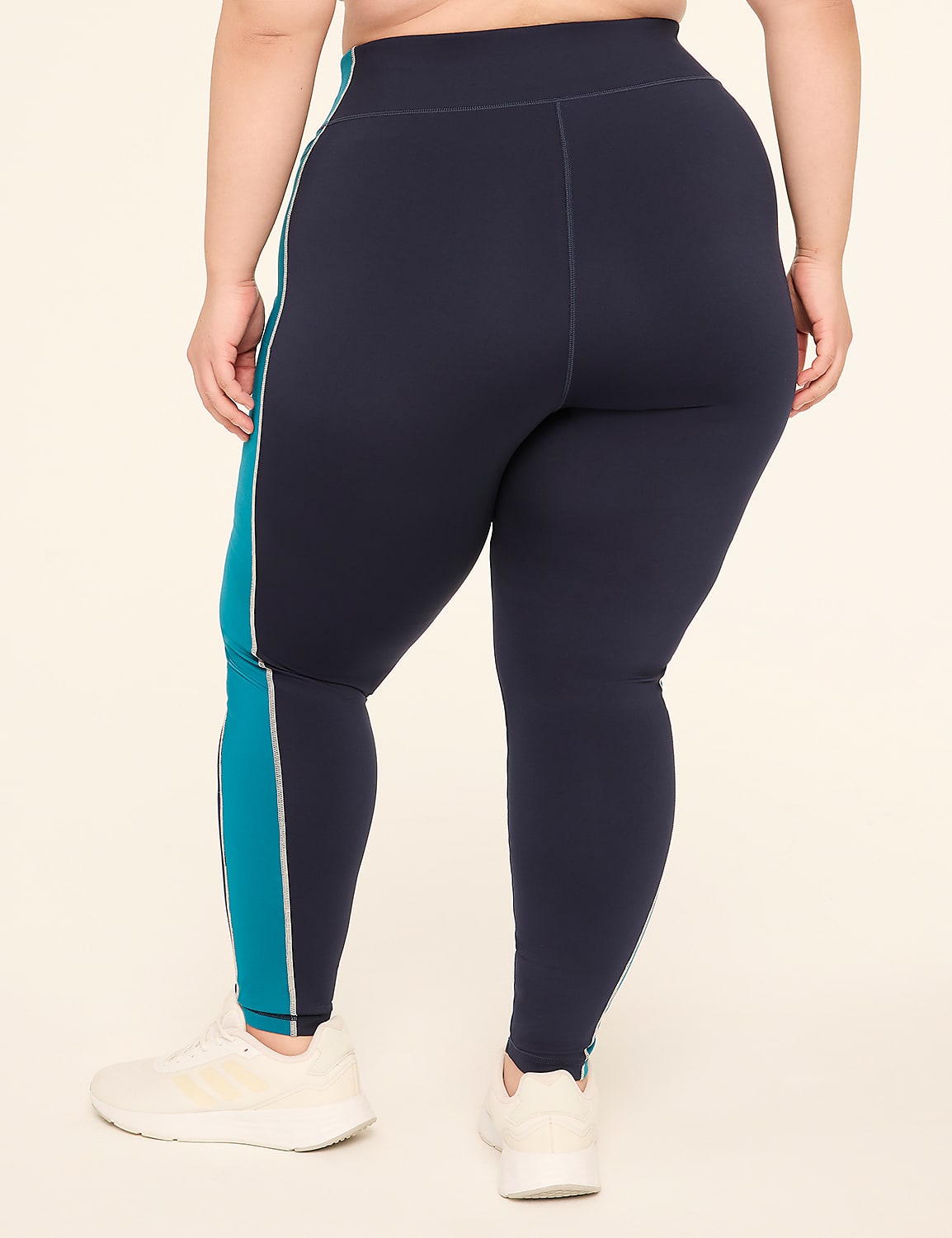A person wearing navy blue leggings with teal stripes stands on a plain, light-colored background. Product Image 2
