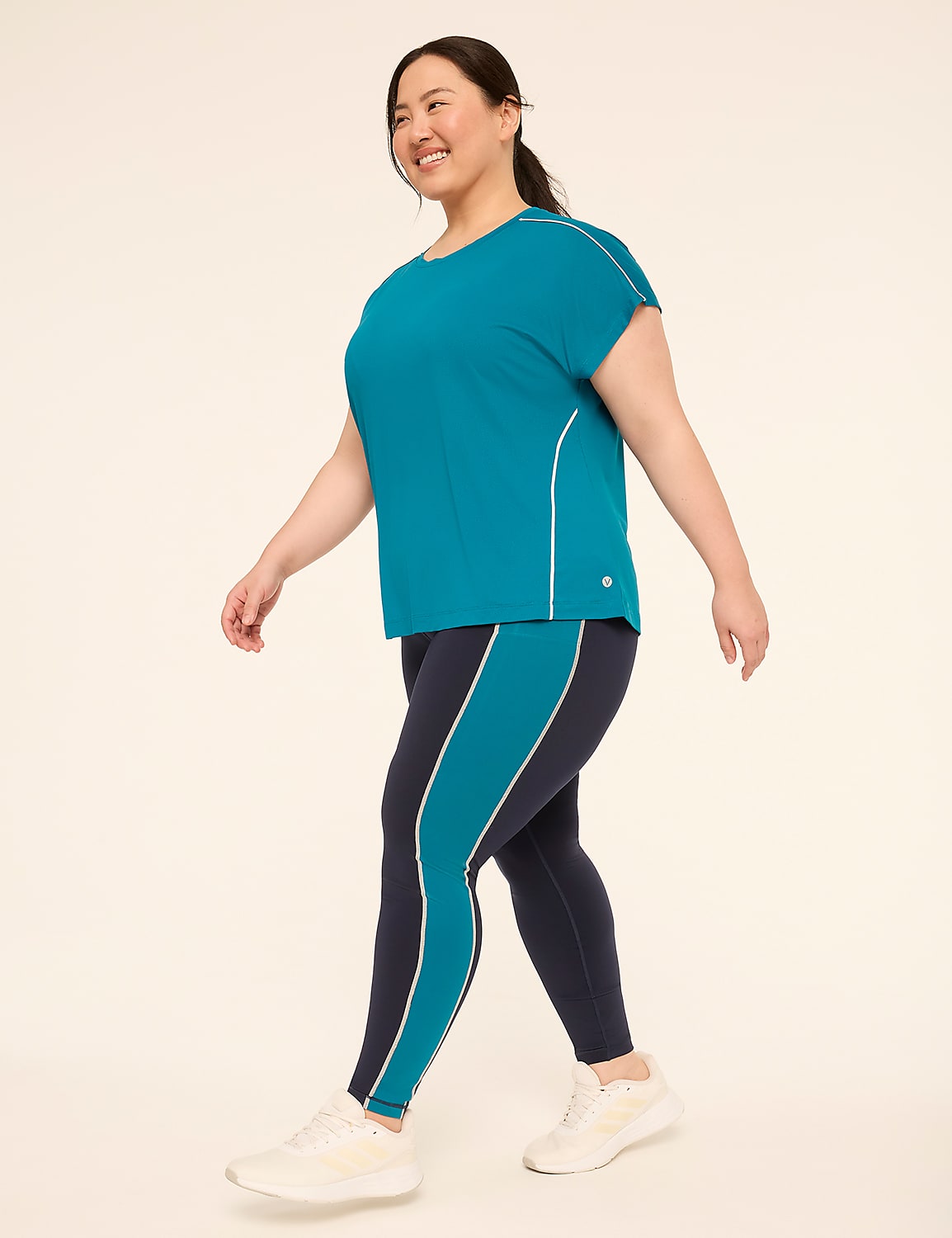 A woman in athletic wear walks against a plain, light-colored background. Product Image 3