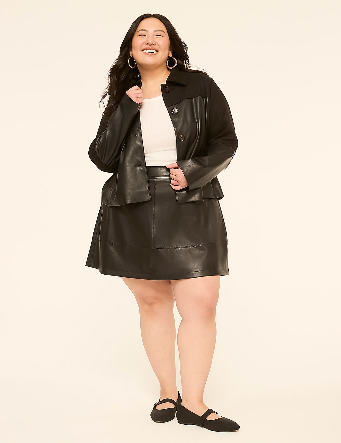 A smiling woman in a black leather outfit stands against a plain, light-colored background. Product Image 3