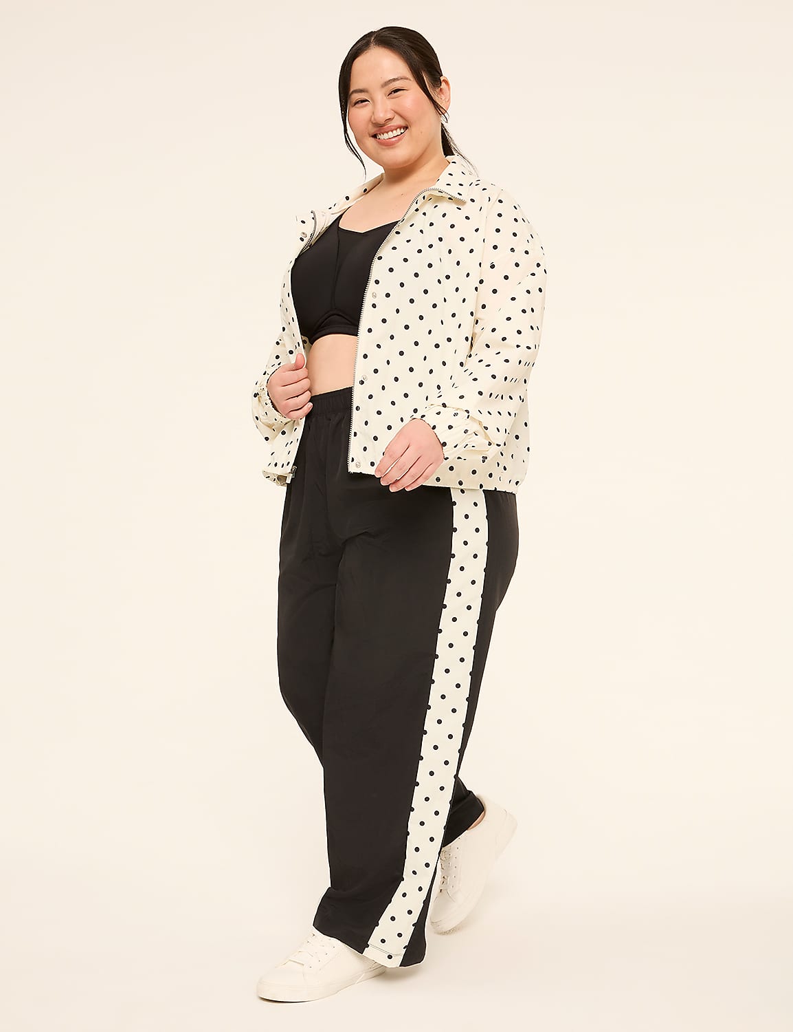 A smiling woman in a polka-dot jacket and black pants stands against a plain, light-colored background. Product Image 3