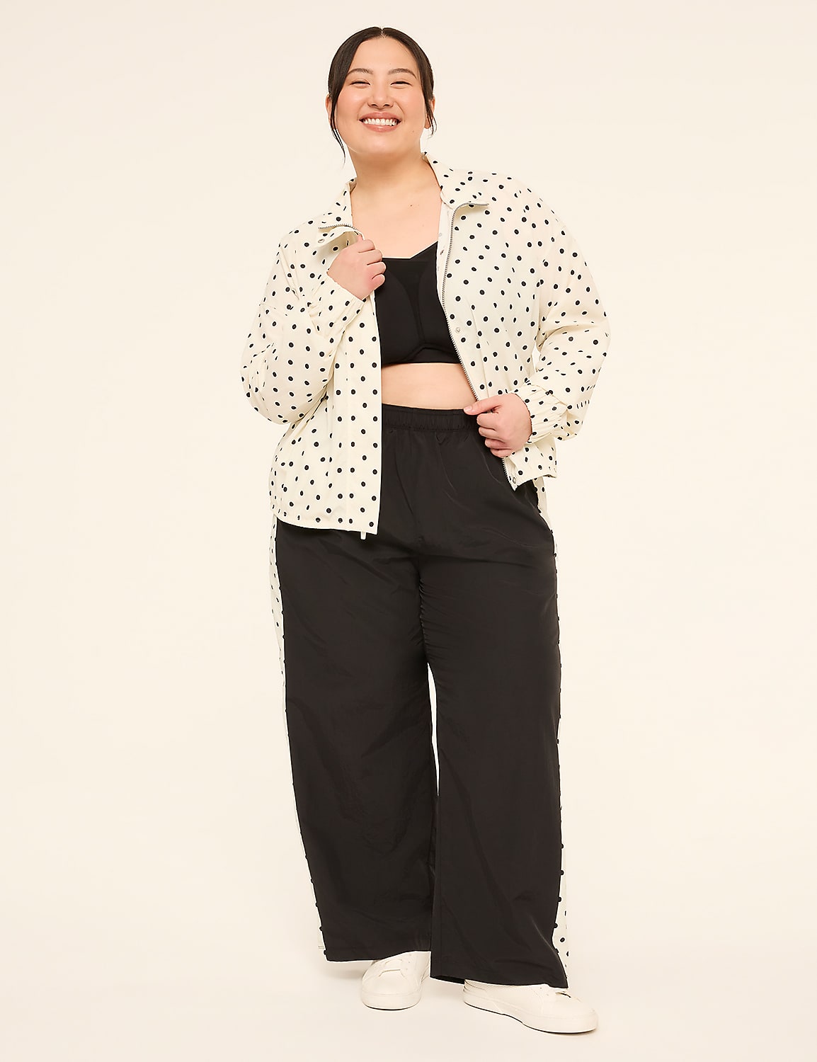 A smiling woman in a polka-dot jacket and black pants stands against a plain, light-colored background. Product Image 3