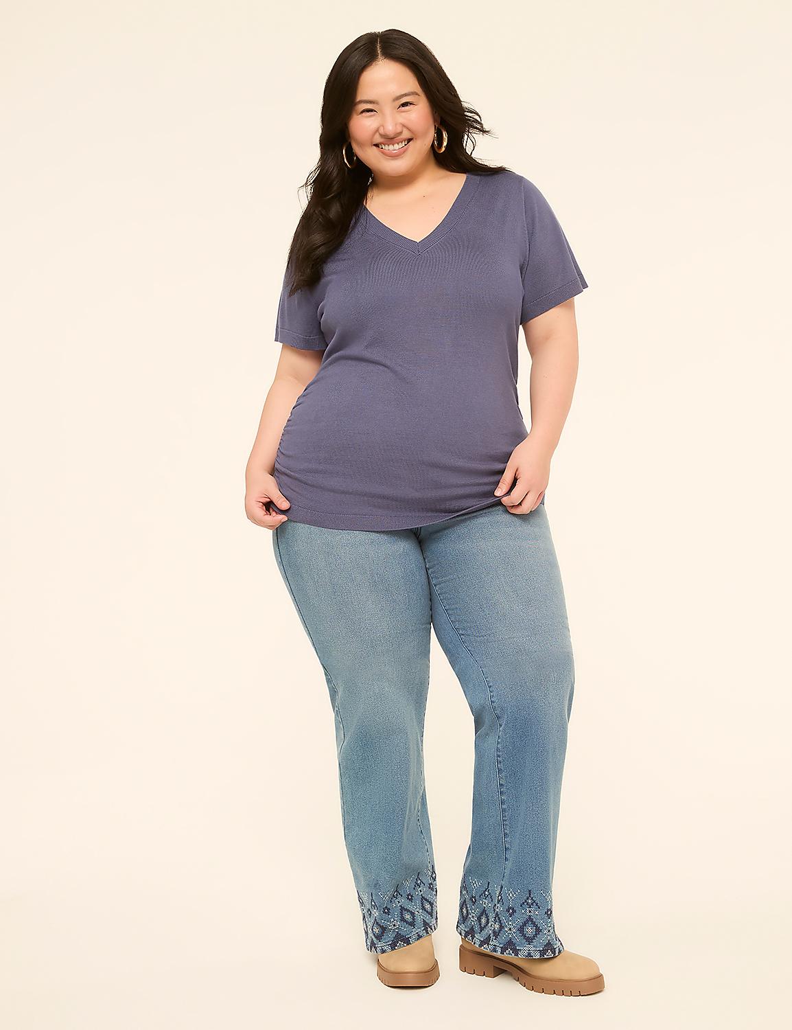 A smiling woman in a blue v-neck shirt and embellished jeans stands against a plain, light-colored background. Product Image 3