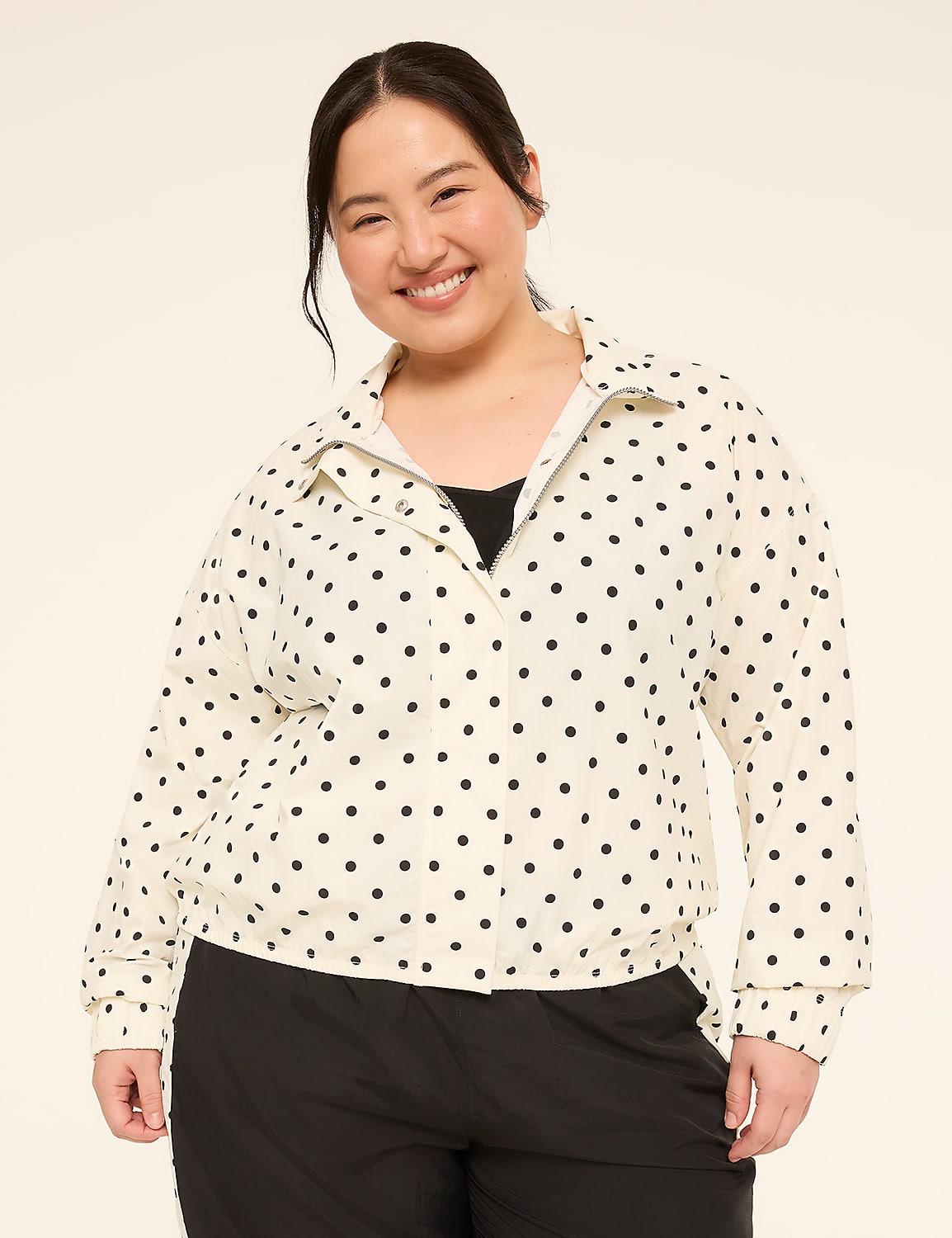 A smiling woman in a polka dot jacket stands against a plain, light-colored background. Product Image 1