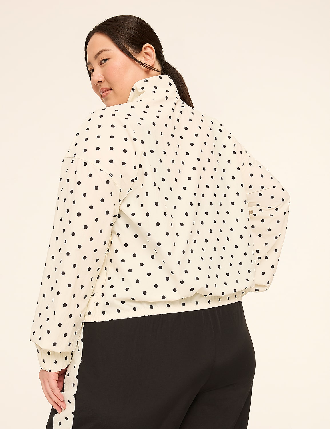 A woman in a polka dot blouse and black pants stands against a plain, light-colored background. Product Image 2