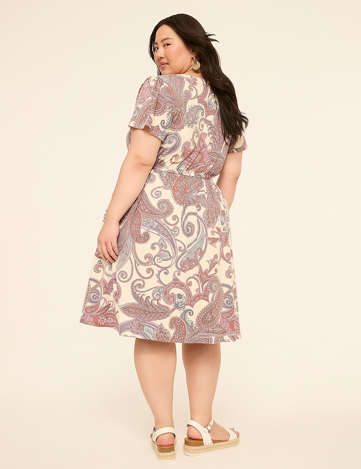 A woman in a paisley print dress stands against a plain, light-colored background. Product Image 2