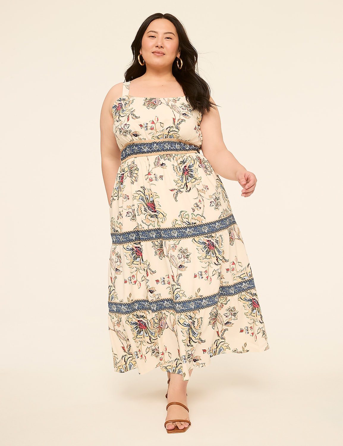 A woman in a floral print dress stands against a plain, light-colored background. Product Image 1