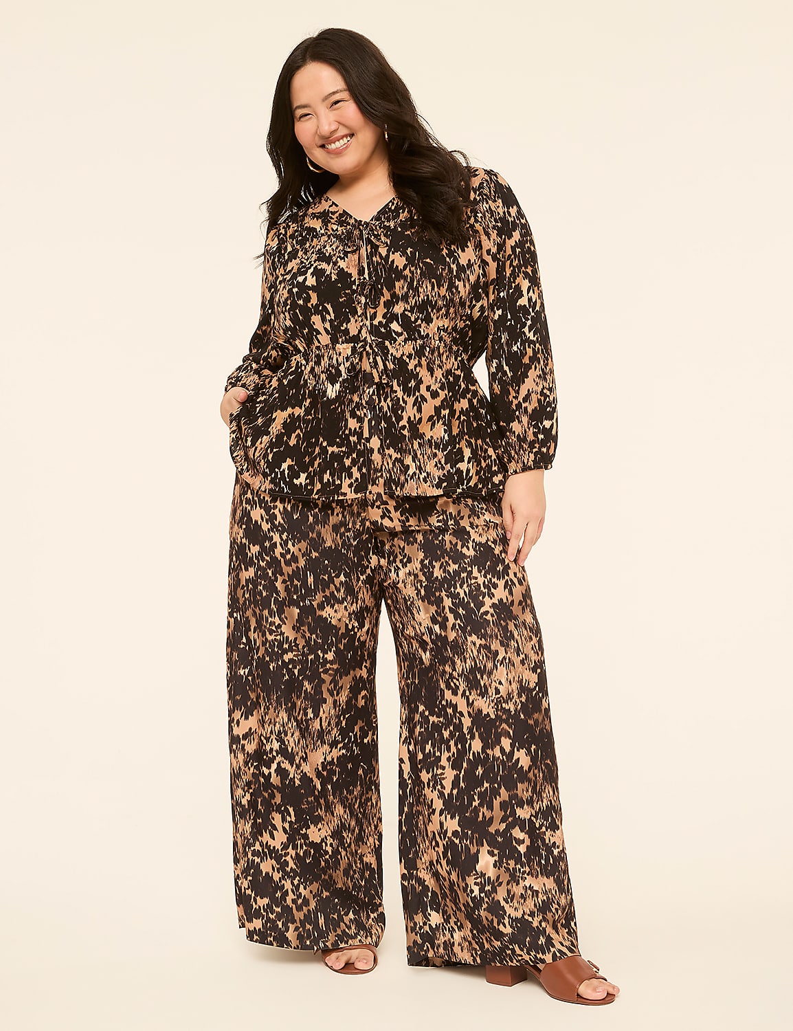 A smiling woman in a patterned top and wide-leg pants stands against a plain, light-colored background. Product Image 3