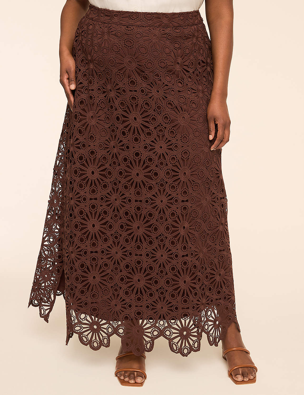 A woman in a brown lace maxi skirt stands against a plain beige background. Product Image 1
