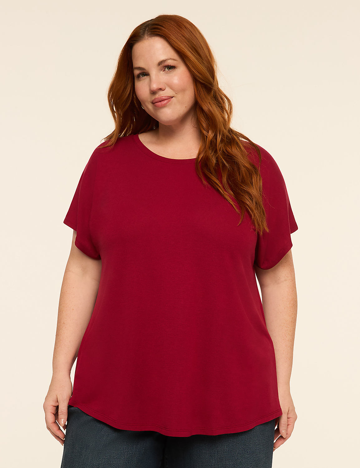 A woman with red hair and a red shirt stands against a plain, light-colored background. Product Image 1