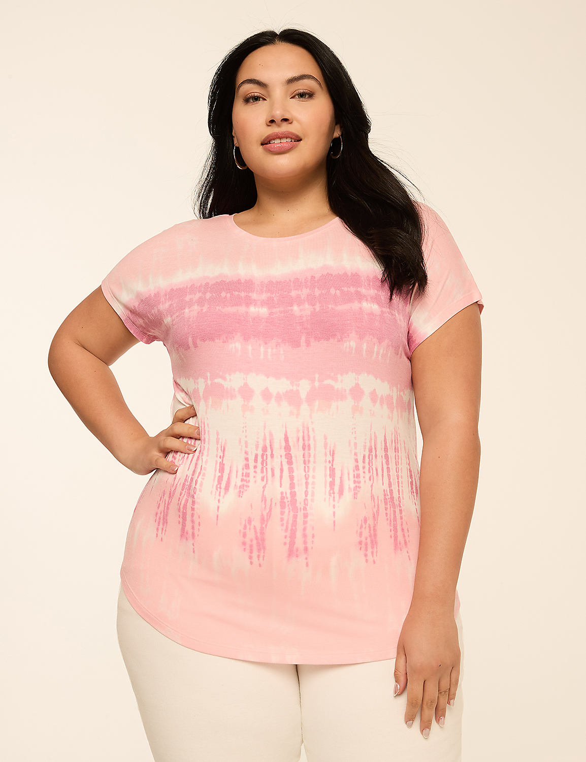A woman in a pink tie-dye t-shirt and white pants poses against a plain, light-colored background. Product Image 1
