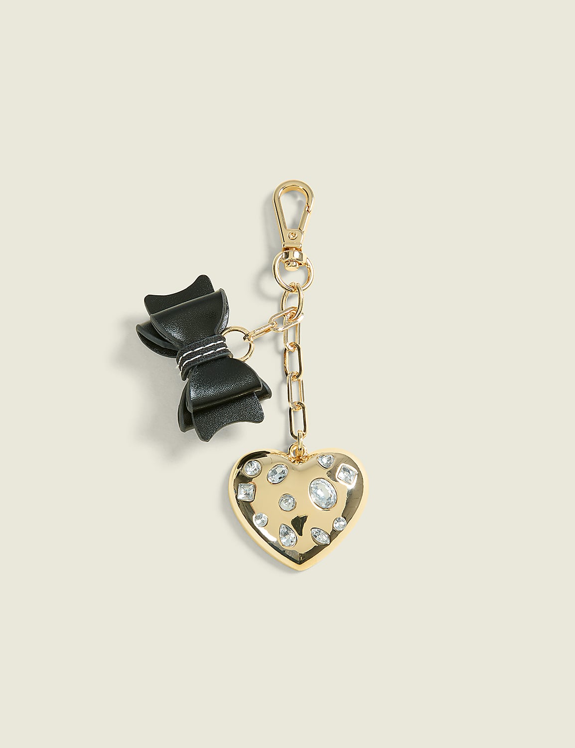 A black bow and a gold heart charm with rhinestones hang from a gold chain against a plain, light background. Product Image 1