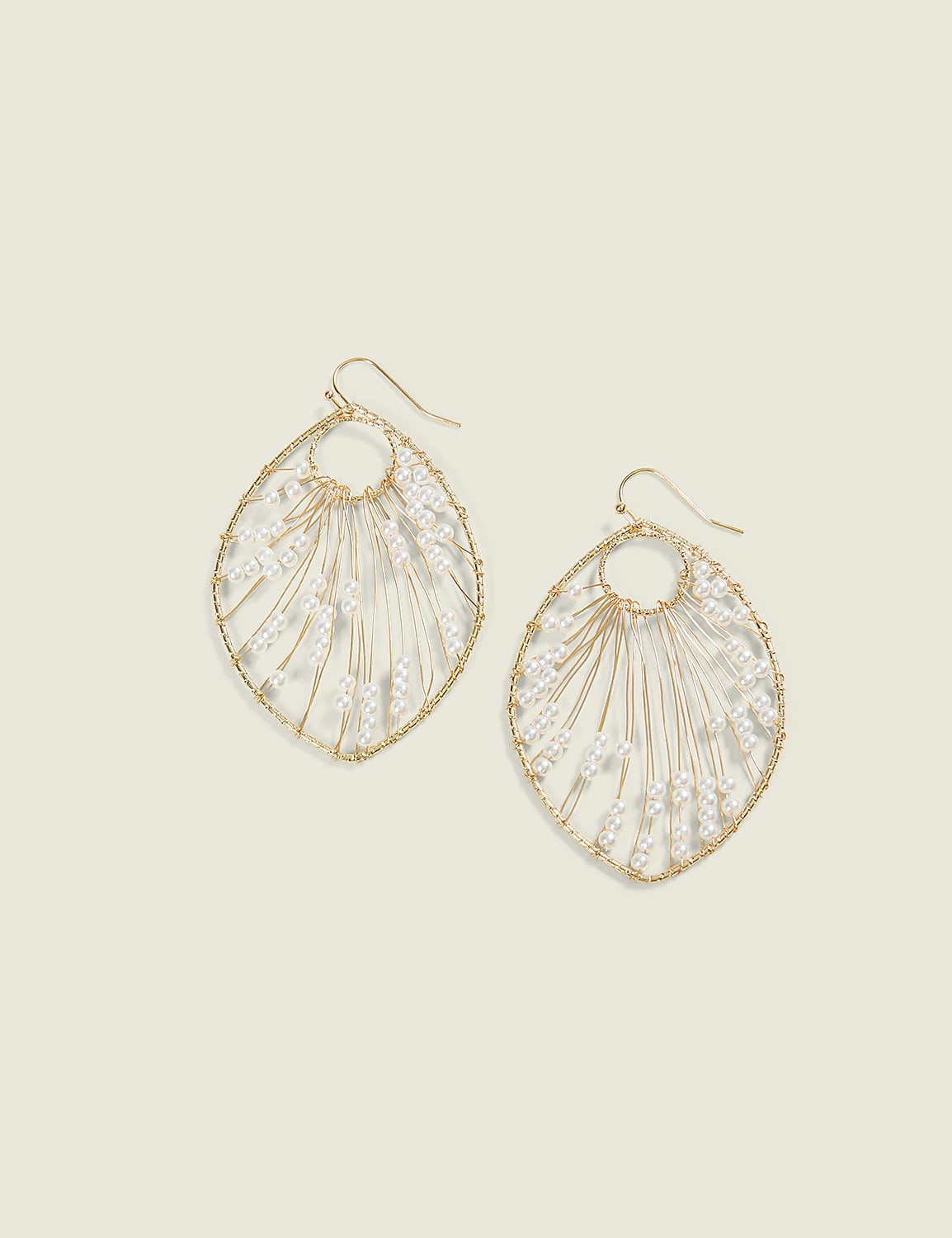 A pair of delicate, gold-toned leaf-shaped earrings with white beaded accents hang against a soft, pale yellow background. Product Image 1