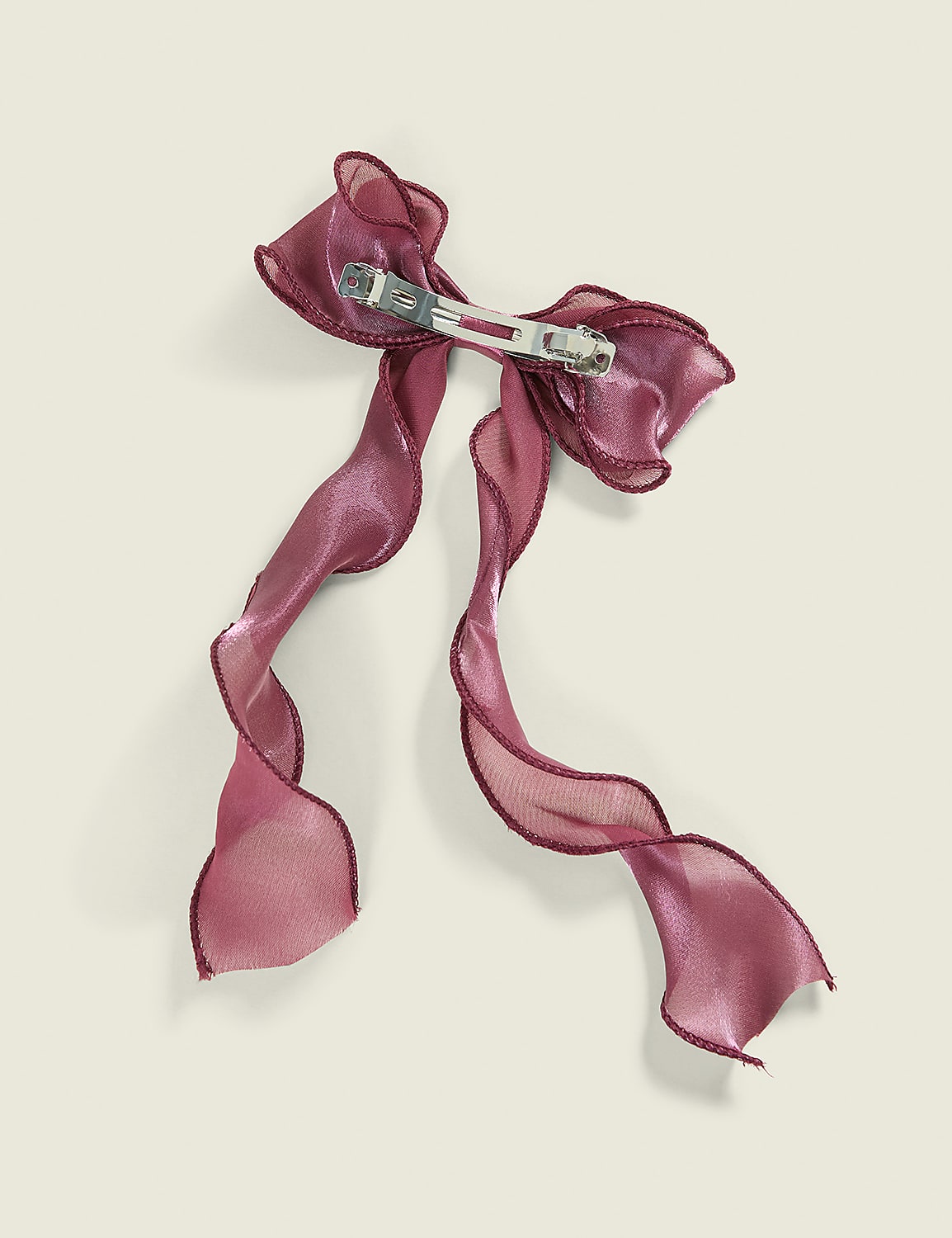 A shimmering pink ribbon bow with a pin backing is set against a plain, light-colored background. Product Image 2