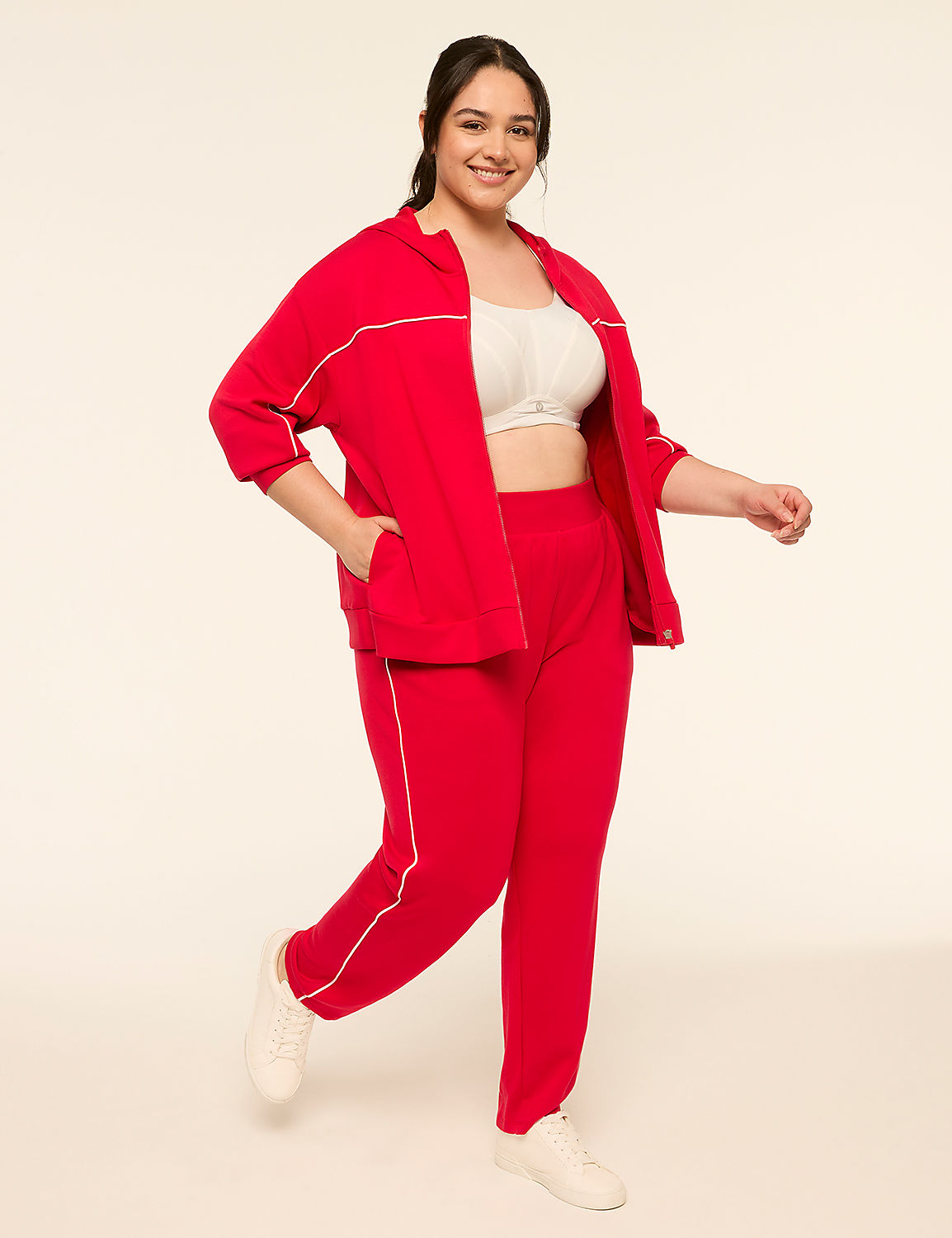 A smiling woman in a red tracksuit with white trim stands against a plain, light-colored background. Product Image 3