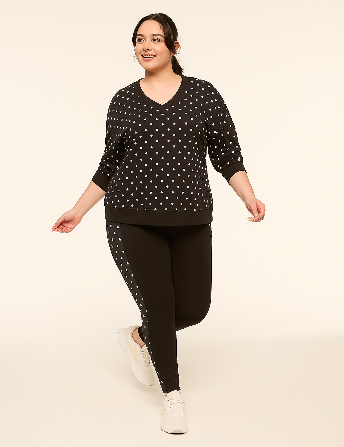 A woman in a black star-patterned sweatshirt and black leggings with a star stripe stands against a plain, light-colored background. Product Image 3