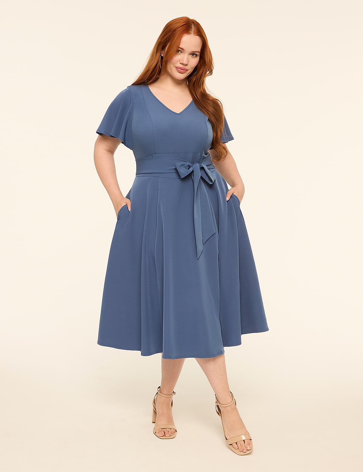 A woman in a blue dress stands with her hands in her pockets against a plain, light background. Product Image 1