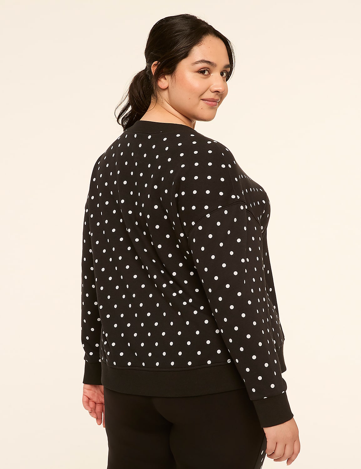 A woman in a black and white polka dot sweatshirt stands against a plain, light-colored background. Product Image 2