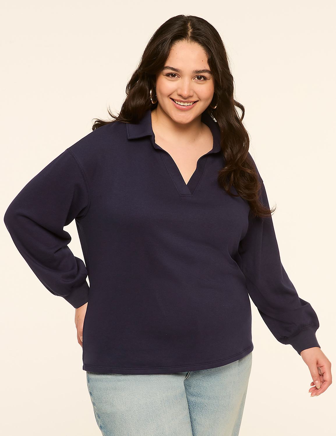 A smiling woman in a navy blue collared shirt and light blue jeans stands against a plain, light-colored background. Product Image 1