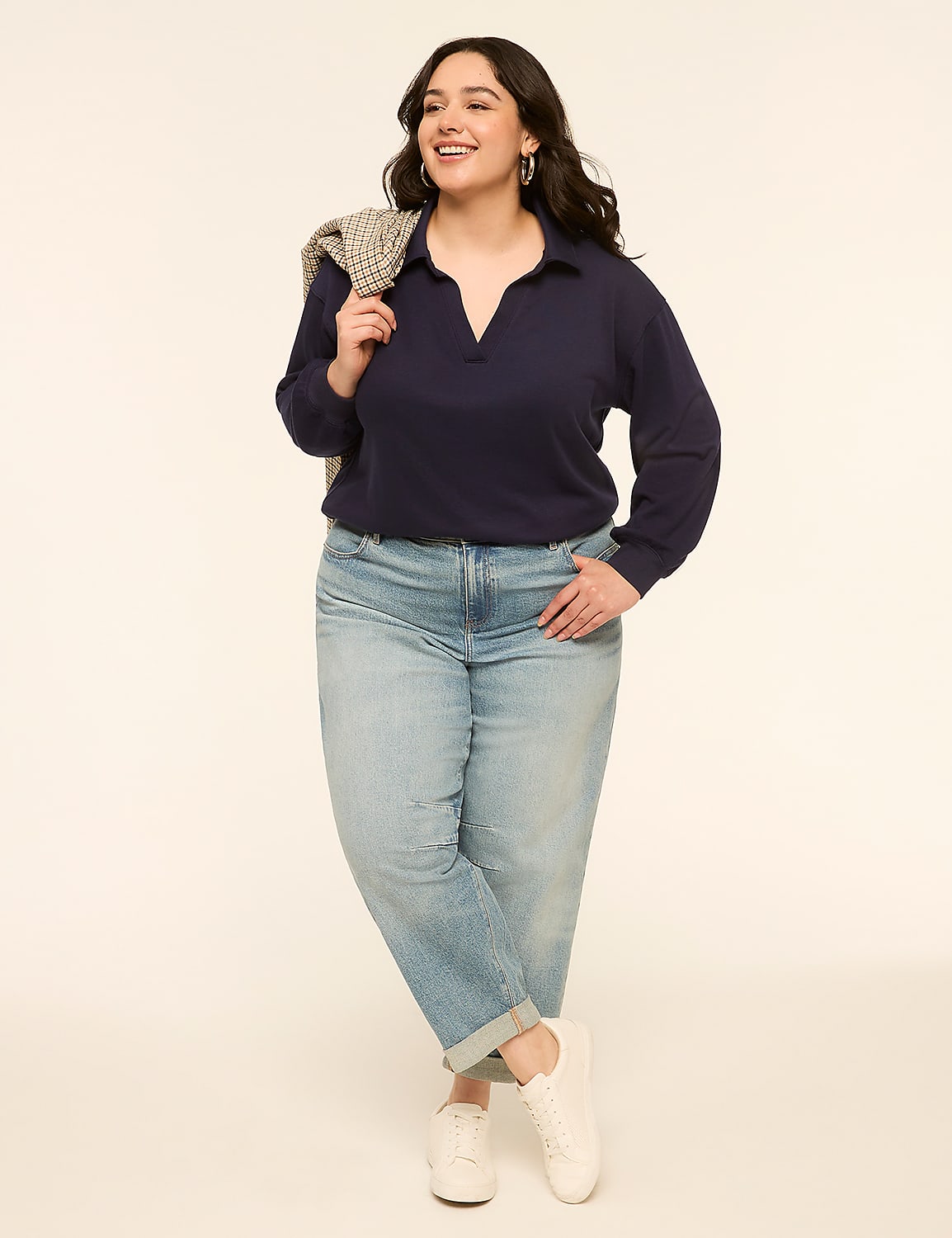 A woman in a navy polo shirt and light-wash jeans stands against a plain, light-colored background, with a patterned jacket draped over her shoulder. Product Image 3