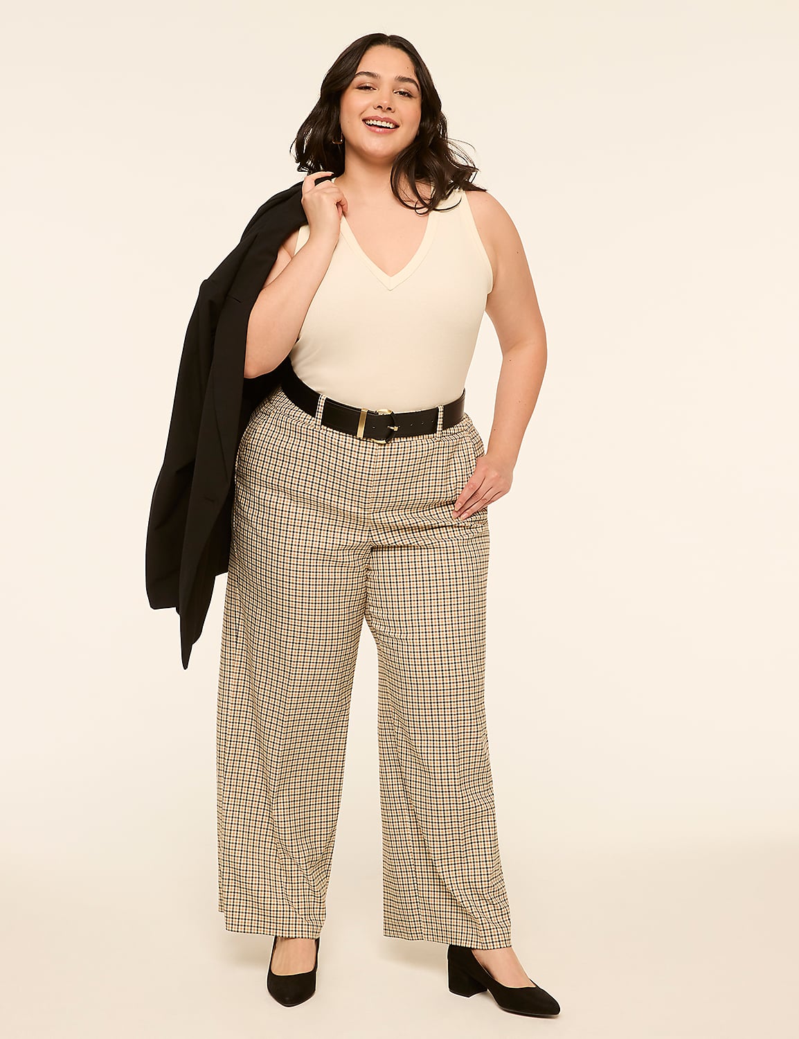 A woman in a cream-colored top, plaid pants, and a black blazer draped over her shoulder stands against a plain, light-colored background. Product Image 3