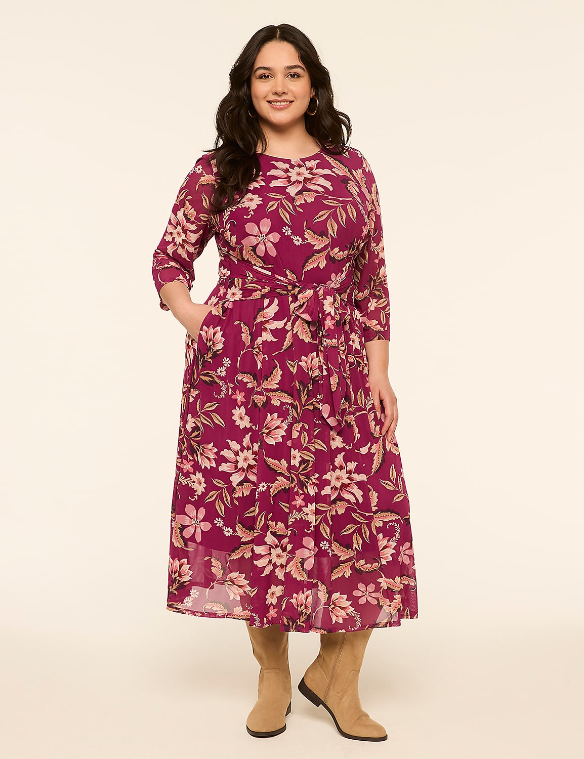 A woman in a floral dress stands against a plain, light-colored background. Product Image 1