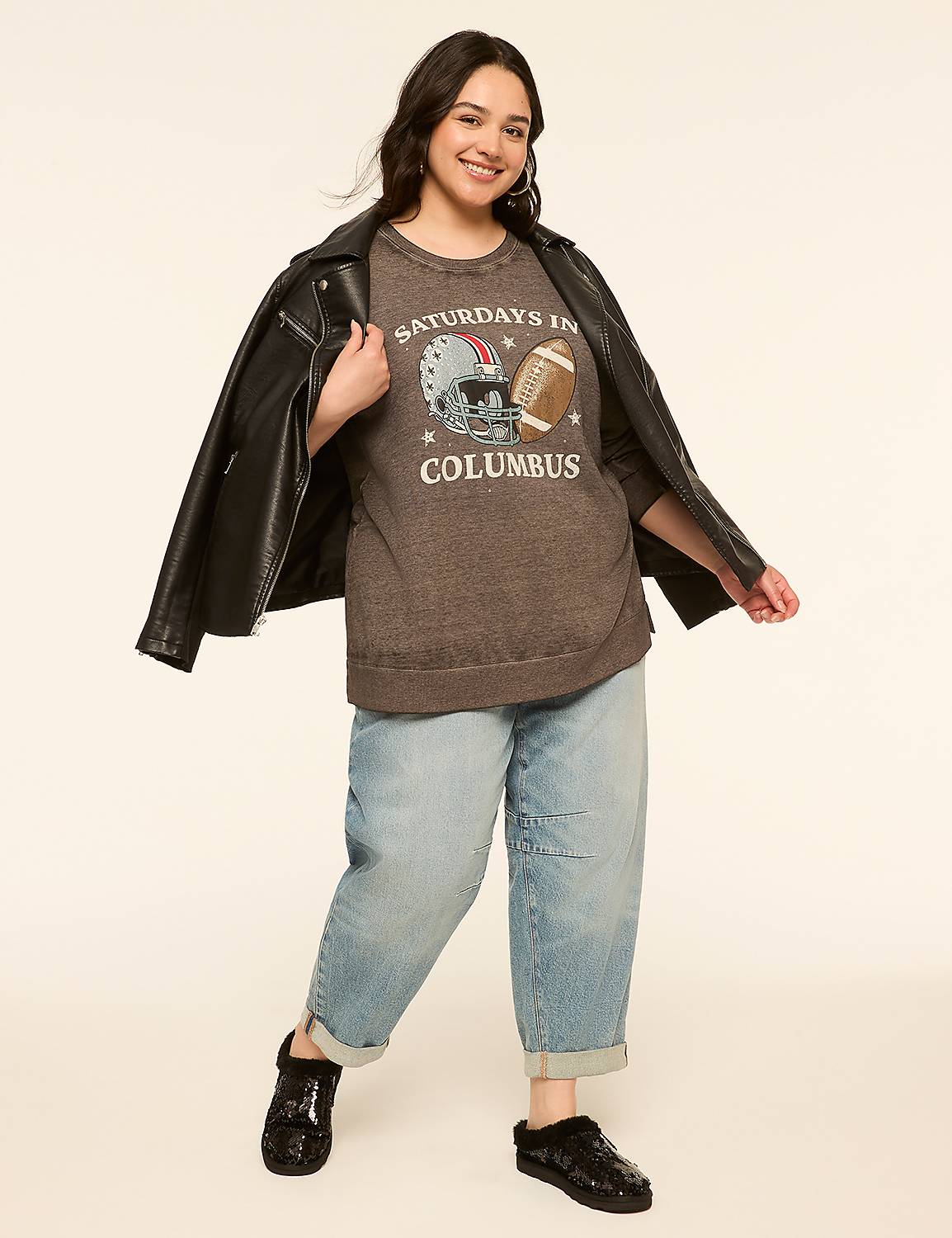 A woman in a graphic t-shirt, baggy jeans, and a leather jacket stands against a plain, light-colored background. Product Image 3