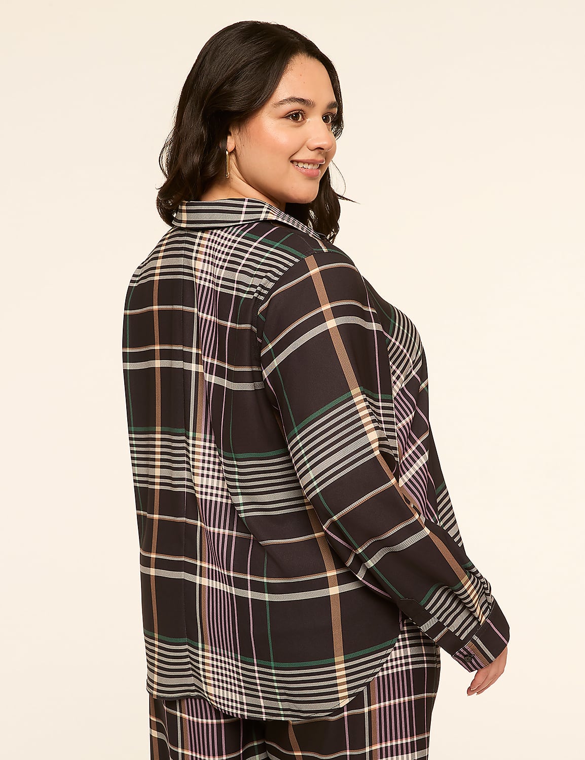 A woman in a plaid shirt and pants smiles over her shoulder against a plain, light-colored background. Product Image 4