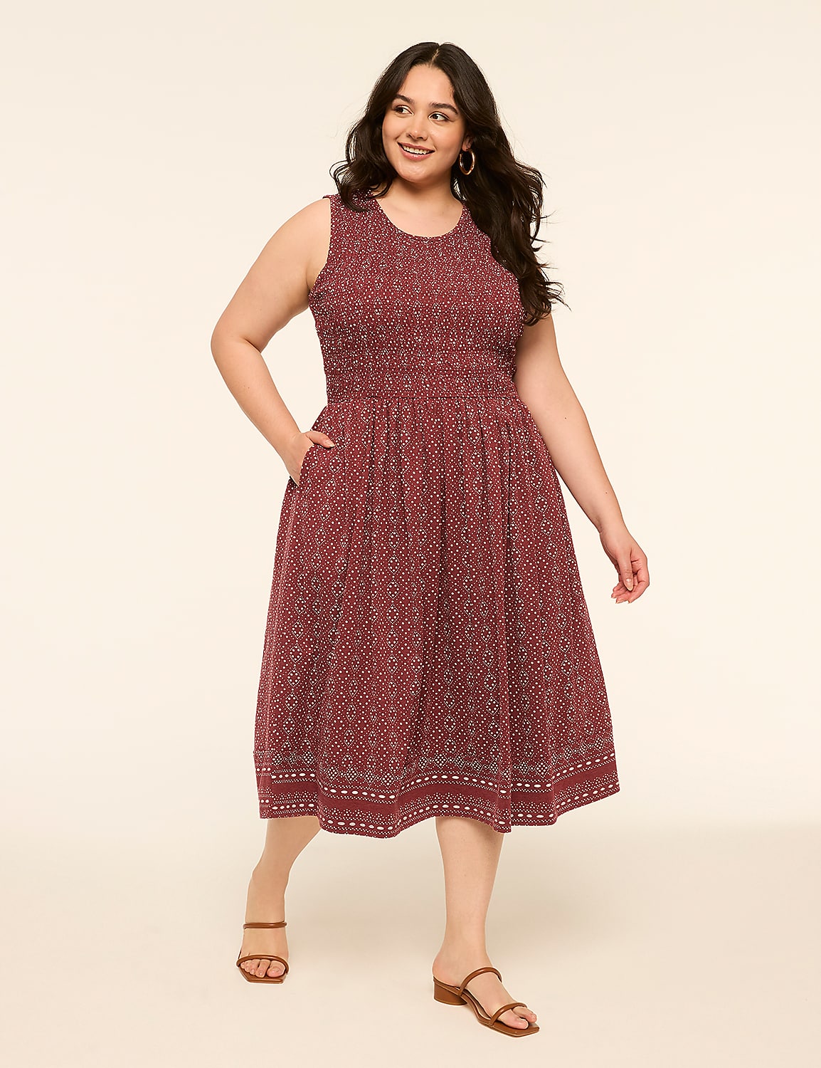 A woman in a patterned maroon dress with her hand in her pocket stands against a plain, light-colored background. Product Image 1