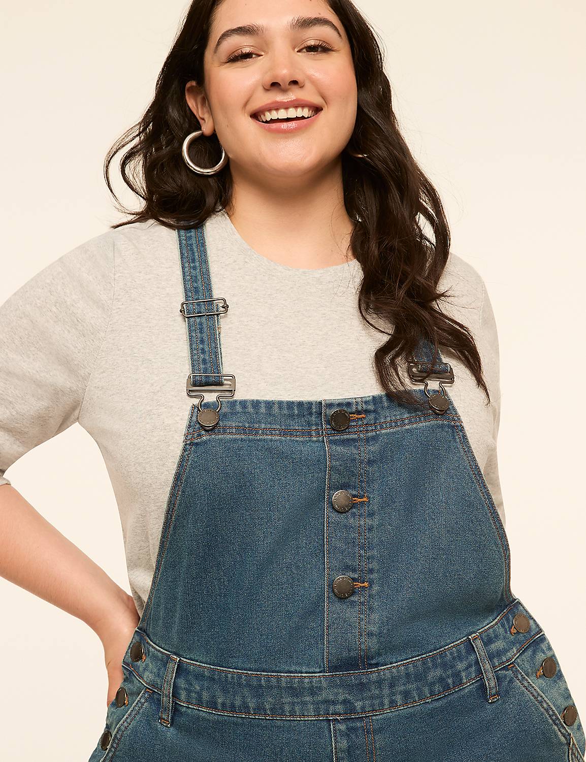 A smiling woman in denim overalls stands against a plain, light-colored background. Product Image 3