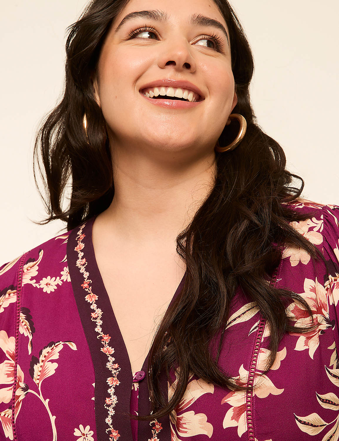 A smiling woman with dark hair and hoop earrings wears a floral print dress against a plain background. Product Image 4