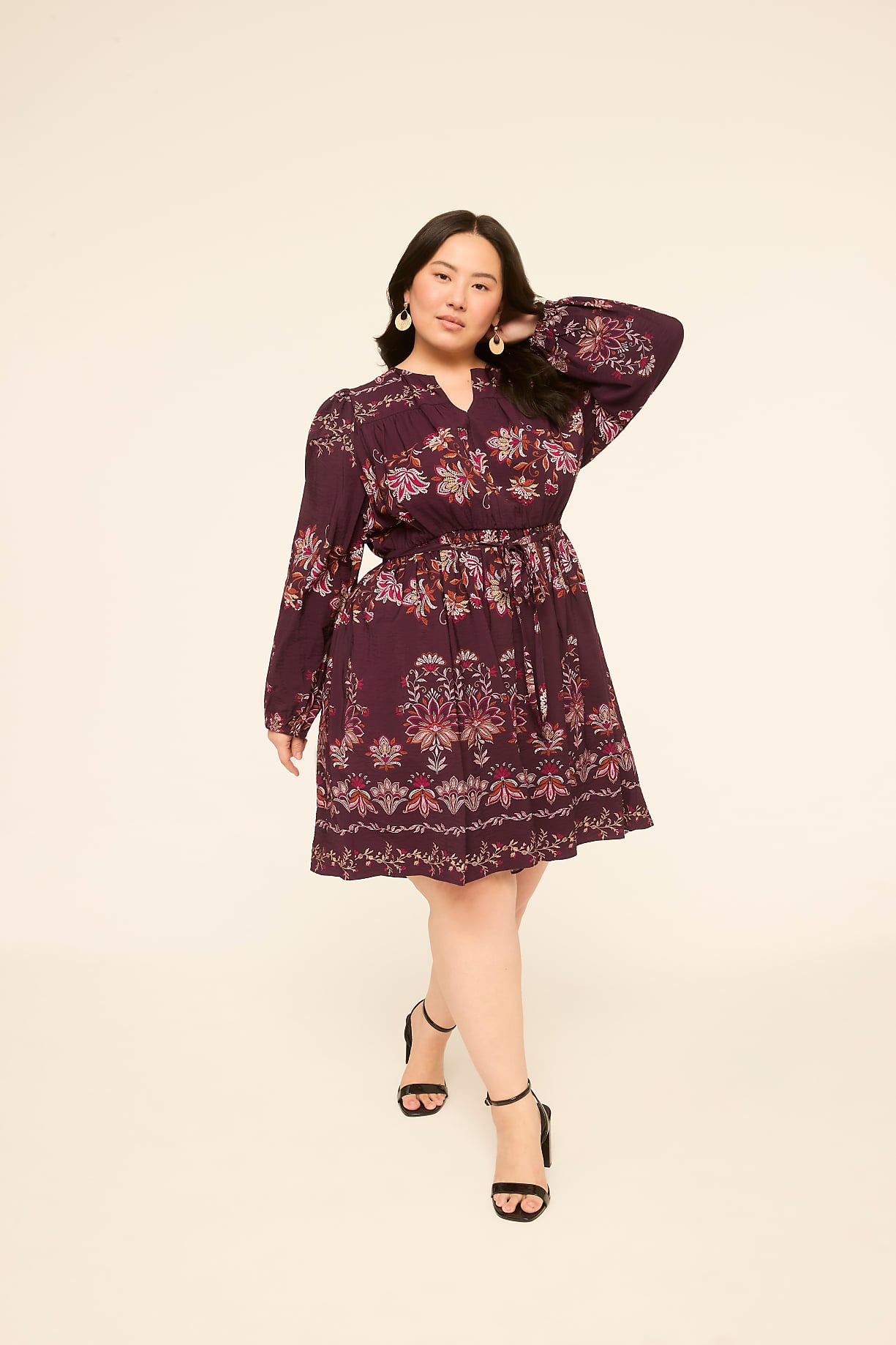 A woman in a floral print dress stands against a plain, light-colored background. Product Image 5