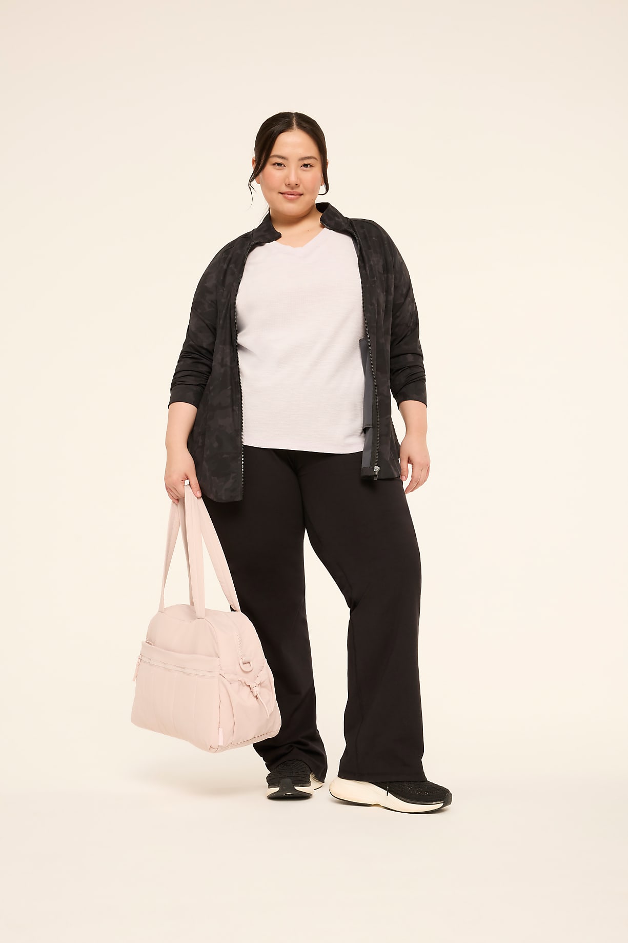A woman in athletic wear stands with a pink duffel bag in front of a plain, light-colored background. Product Image 4
