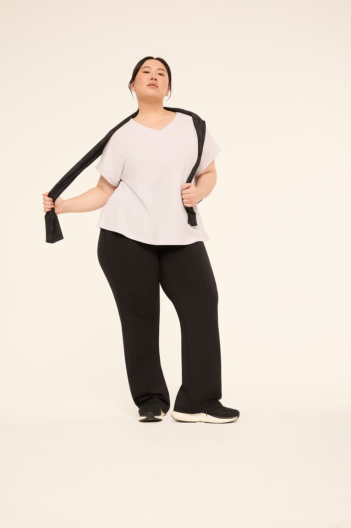 A woman in a light grey t-shirt and black pants stands with a black scarf draped over her shoulders against a plain, light-colored background. Product Image 6