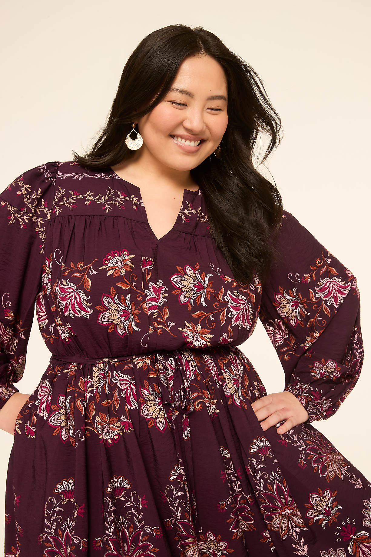 A smiling woman in a floral dress stands against a plain background. Product Image 7